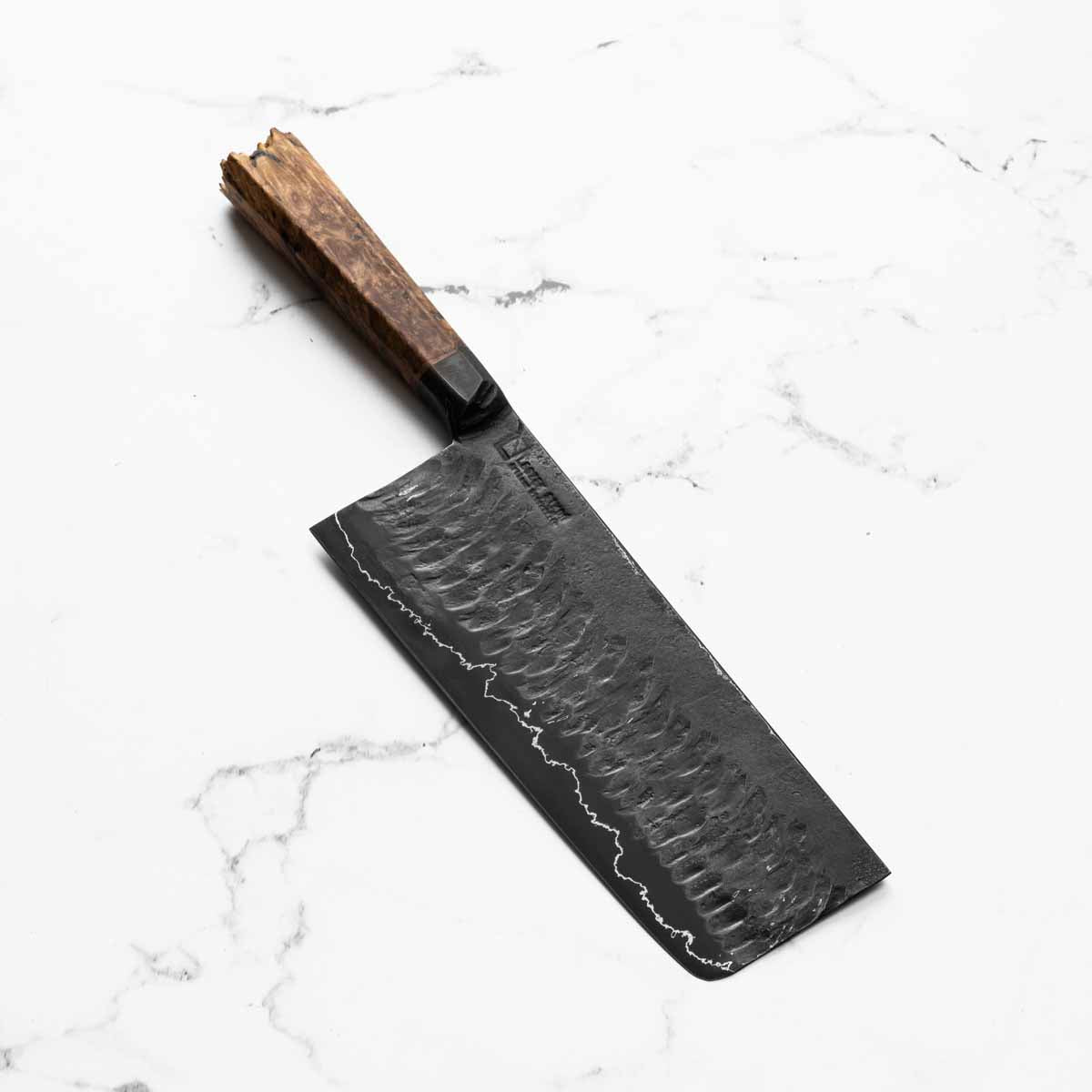 Black chef's knife with a wooden handle on a white marble surface